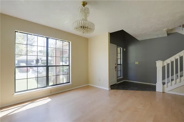 an empty room with wooden floor fireplace and windows