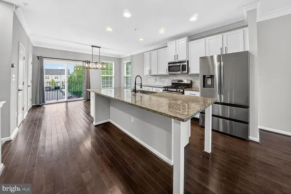 a kitchen with kitchen island granite countertop stainless steel appliances cabinets a sink and a counter top space