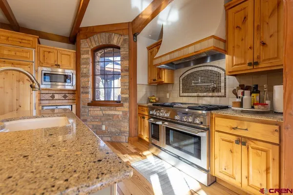 a kitchen with stainless steel appliances granite countertop a stove a sink and a microwave