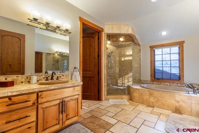 a spacious bathroom with a double vanity sink a mirror and a shower