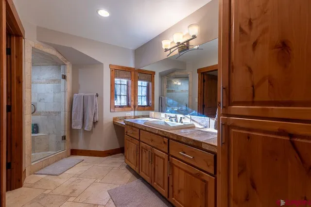 a bathroom with a granite countertop sink a large mirror and a shower