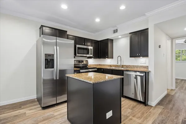 a kitchen with stainless steel appliances granite countertop a refrigerator a sink a stove a microwave and wooden floor