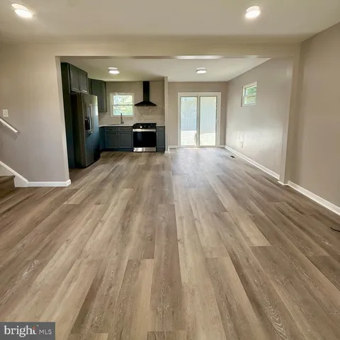 a view of empty room with wooden floor and a window