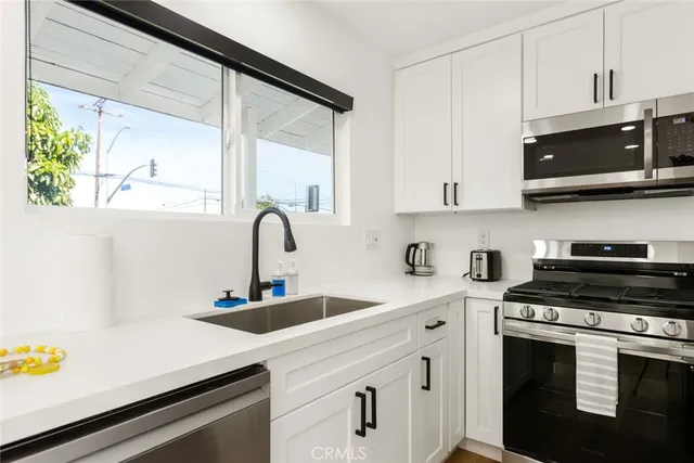 a kitchen with stainless steel appliances a sink a stove and a microwave