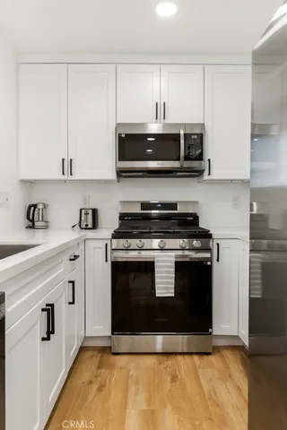 a kitchen with stainless steel appliances granite countertop a stove a sink and a microwave