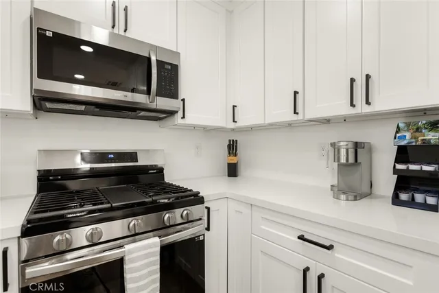 a kitchen with stainless steel appliances granite countertop white cabinets and a stove top oven