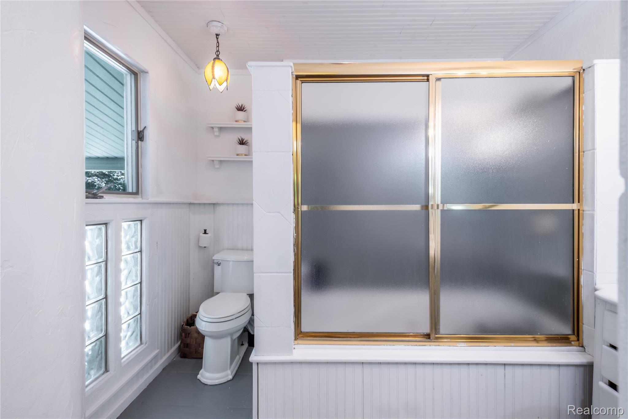4418 North Gale Road Davison, MI 48423 - Photo 35 of 46 Bathroom featuring a gold-framed shower with frosted glass doors, white beadboard paneling, and a transom window