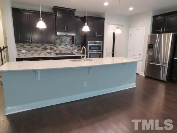 a large kitchen with a wooden floor and a refrigerator