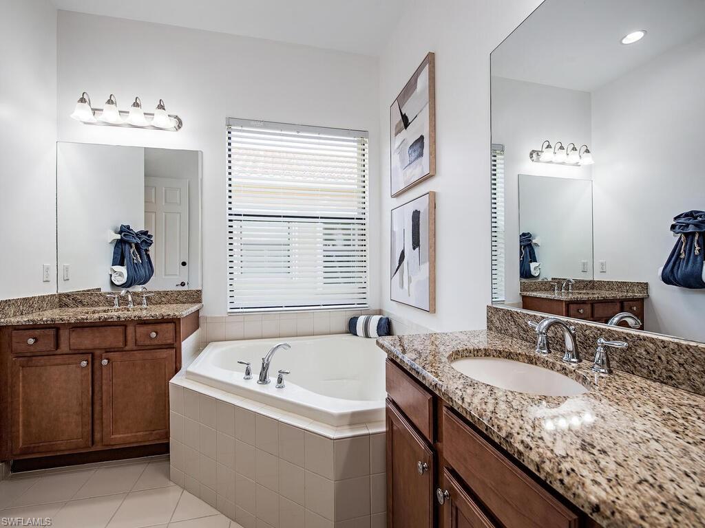 3487 Pacific Drive Naples, FL 34119 - Photo 11 of 33 a bathroom with a granite countertop bathtub sink and mirror