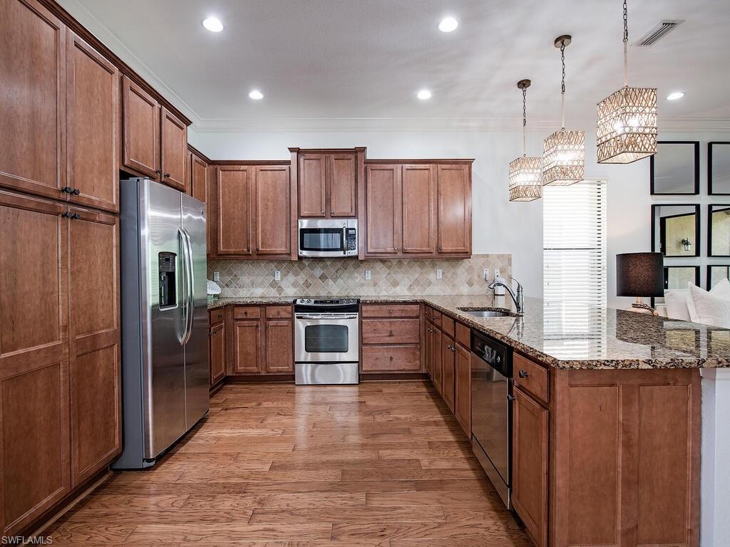 3487 Pacific Drive Naples, FL 34119 - Photo 6 of 33 a large kitchen with stainless steel appliances granite countertop a refrigerator a sink dishwasher a stove and a microwave oven on the wooden floor