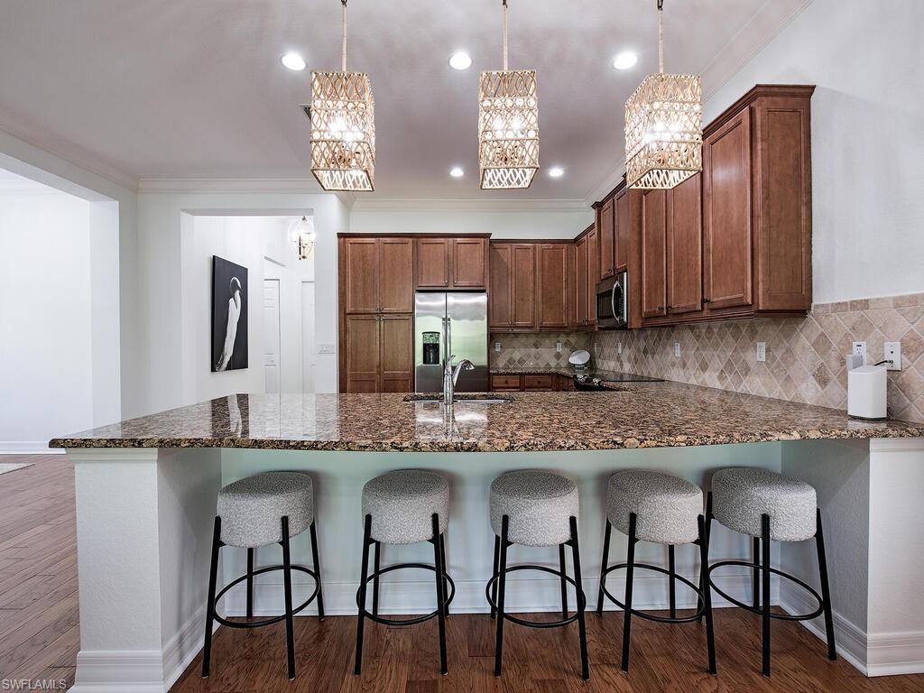 3487 Pacific Drive Naples, FL 34119 - Photo 7 of 33 a kitchen with cabinets a sink stainless steel appliances and dining table