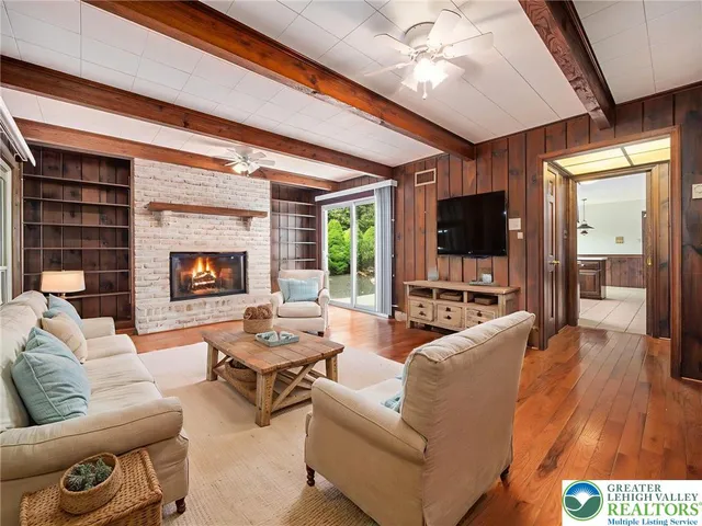 a view of an empty room with wooden floor fireplace and a window