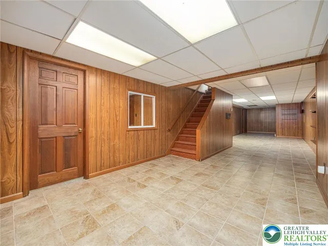 an empty room with wooden floor chandelier fan and windows