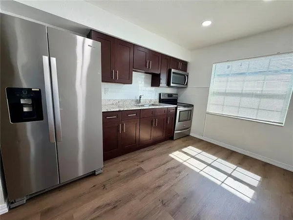 a kitchen with stainless steel appliances granite countertop a refrigerator and a stove top oven