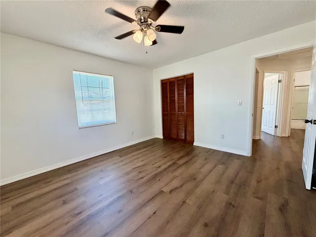 a view of empty room with wooden floor and fan
