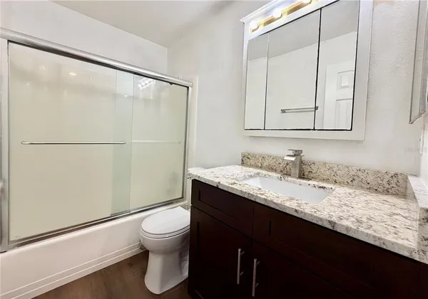a bathroom with a granite countertop sink toilet a mirror and shower