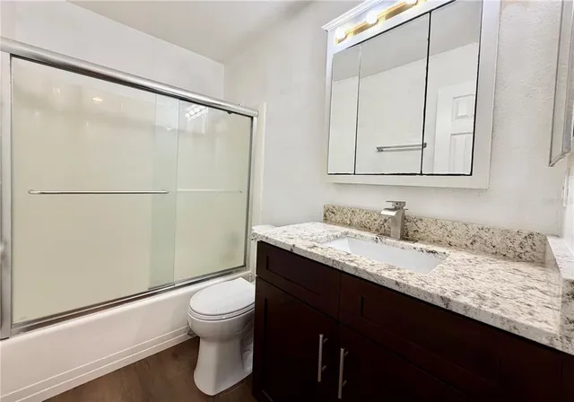 a bathroom with a granite countertop sink toilet a mirror and shower