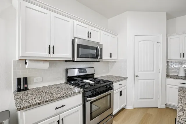 a kitchen with kitchen island granite countertop a sink a stove and cabinets