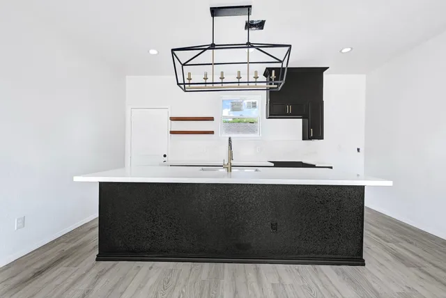 a view of an empty room with wooden floor and a ceiling fan