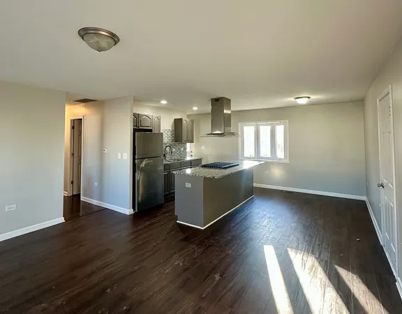 a kitchen with stainless steel appliances granite countertop a refrigerator a sink a stove and white cabinets with wooden floor