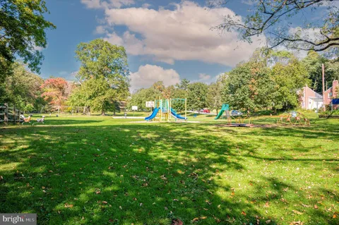 a view of a white house with a big yard and large trees