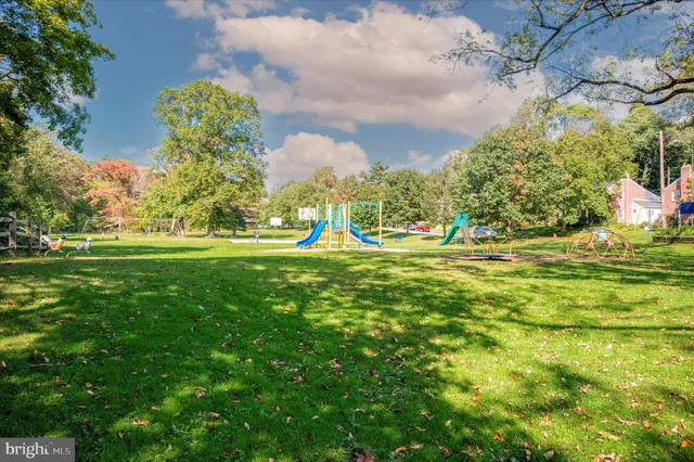a view of a white house with a big yard and large trees