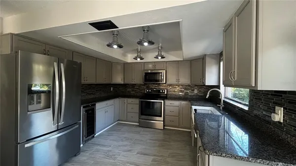 a kitchen with stainless steel appliances granite countertop a refrigerator a stove and a sink