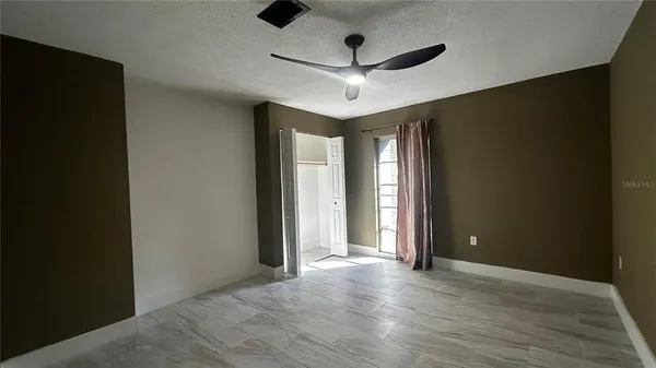 an empty room with wooden floor and ceiling fan