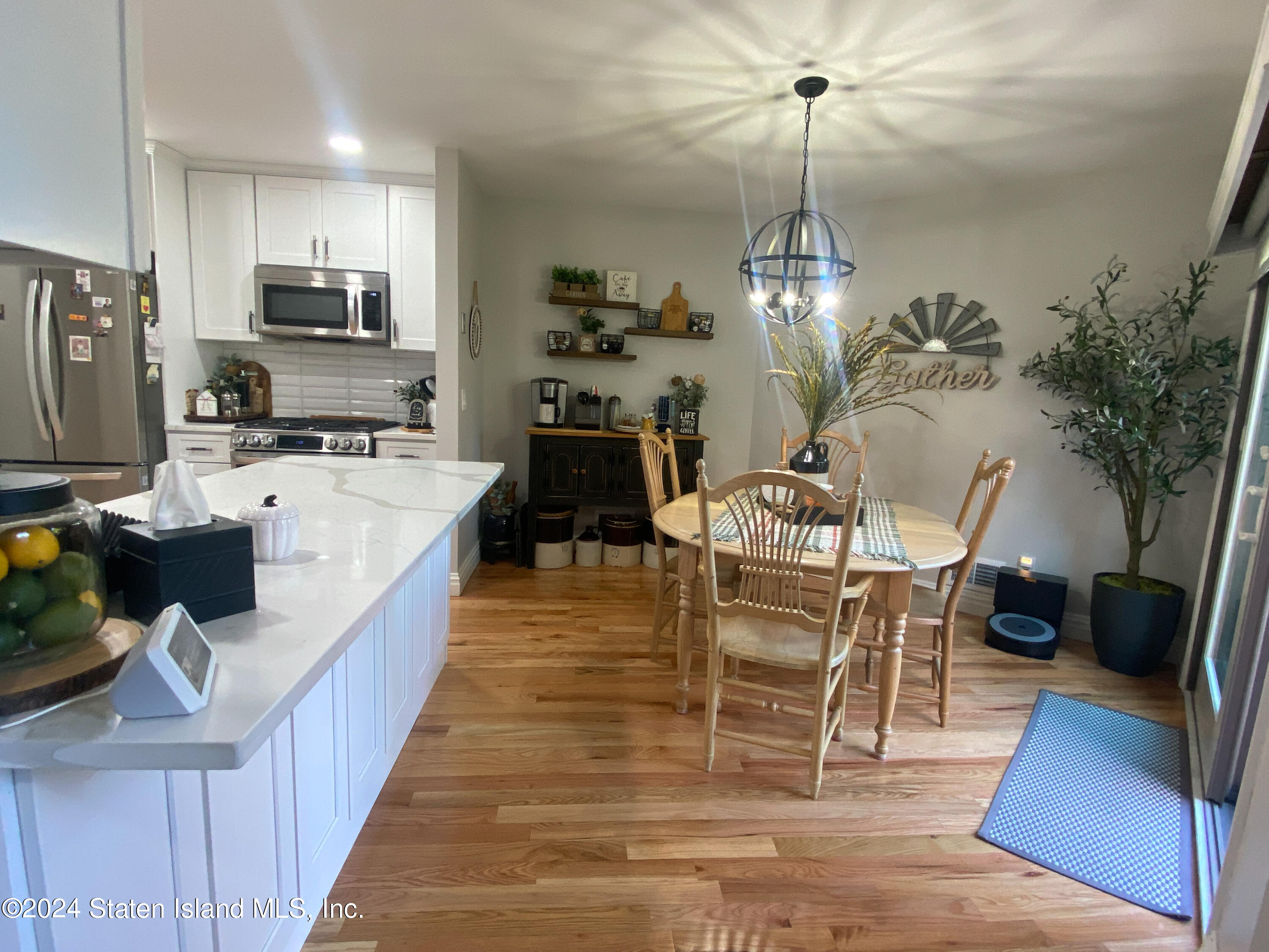 1440 Forest Hill Road, Unit 2 Staten Island, NY 10314 - Photo 7 of 32 a dining room with wooden floor a chandelier a wooden table and chairs