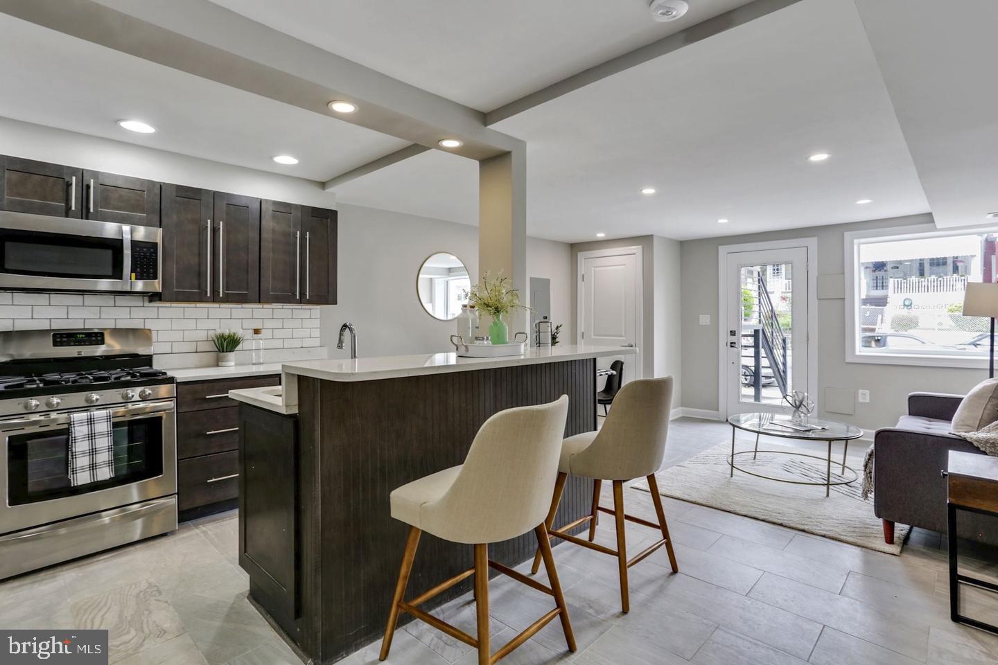 a kitchen with stainless steel appliances kitchen island granite countertop a stove a sink a microwave a dining table and chairs