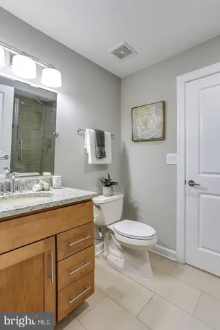 a bathroom with a granite countertop toilet a sink and mirror