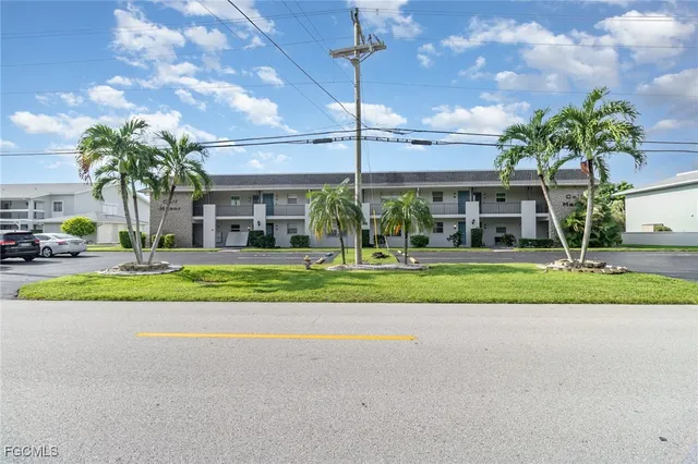 a view of a house with a big yard and palm trees