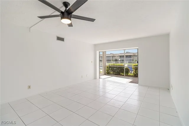 an empty room with floor to ceiling windows and a ceiling fan
