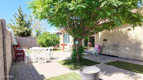 a view of a patio with table and chairs potted plants and large tree