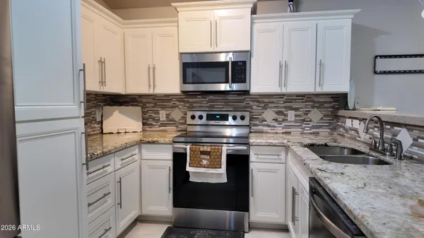 a kitchen with granite countertop a sink stove and microwave