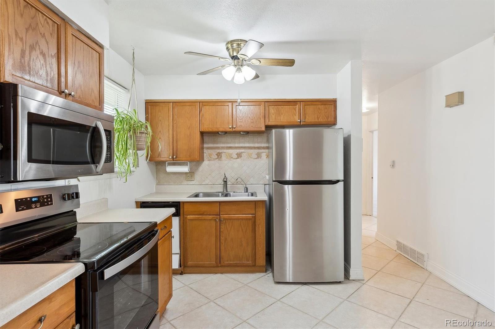 200 Perry Street Denver, CO 80219 - Photo 7 of 24 a kitchen with stainless steel appliances a refrigerator a stove a sink and a microwave