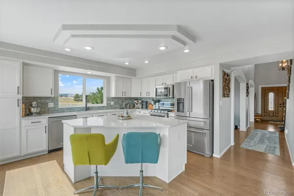 a kitchen with stainless steel appliances granite countertop a refrigerator a stove top oven and a center island