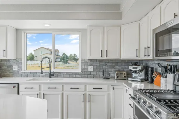 a kitchen with stainless steel appliances granite countertop a stove a sink and a microwave