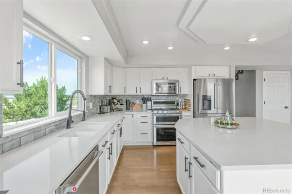 a kitchen with stainless steel appliances kitchen island granite countertop a sink stove and refrigerator