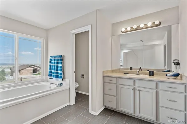 a spacious bathroom with a tub double sink and mirror
