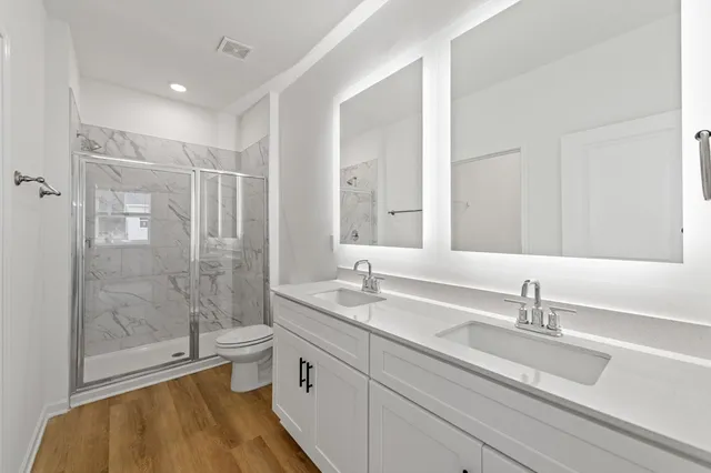 a bathroom with a double vanity sink toilet a mirror and shower