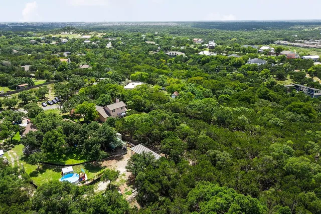 an aerial view of residential house with outdoor space and trees all around
