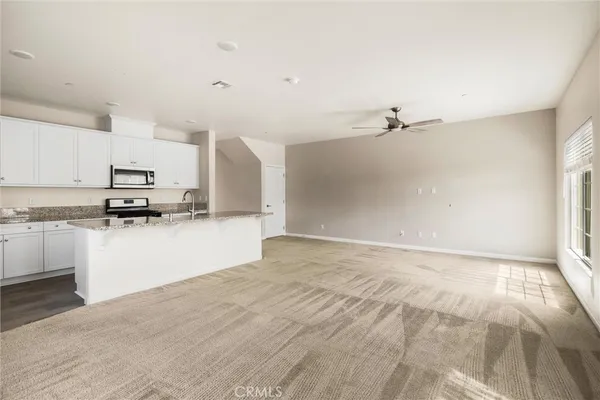 a kitchen with granite countertop a refrigerator oven a sink and white cabinets