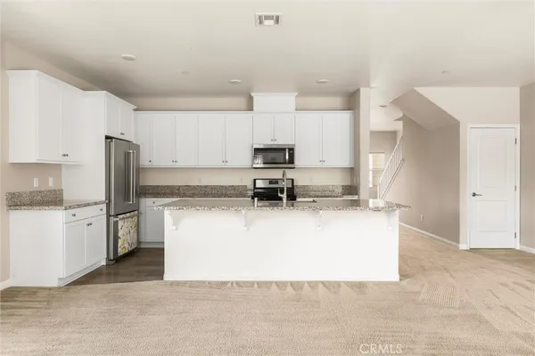 a kitchen with stainless steel appliances granite countertop a stove a refrigerator and a stove top oven