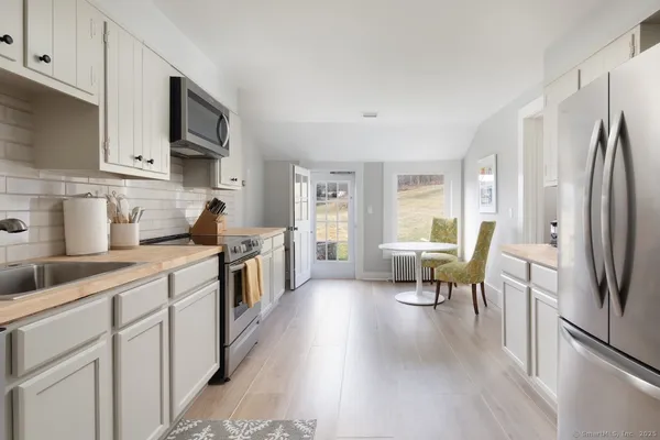 a kitchen with stainless steel appliances a refrigerator a sink dishwasher a stove and white cabinets with wooden floor