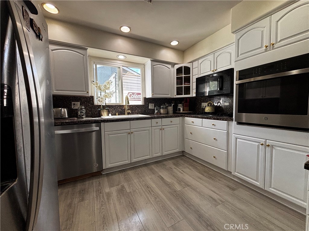 5604 Tower Road Riverside, CA 92506 - Photo 27 of 70 a kitchen with stainless steel appliances kitchen island granite countertop a sink a microwave a refrigerator and cabinets