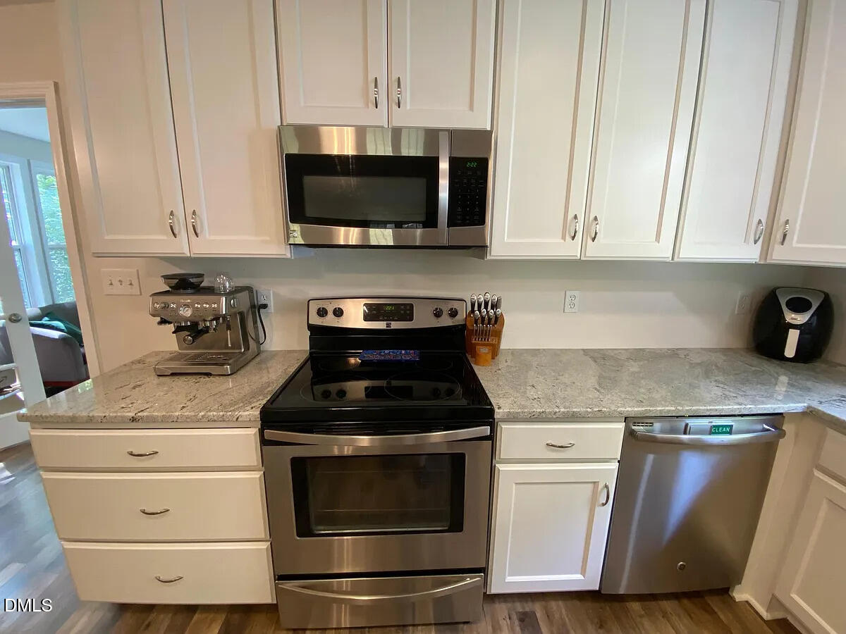 7501 Post Oak Road Raleigh, NC 27615 - Photo 8 of 40 a kitchen with granite countertop white cabinets and black appliances