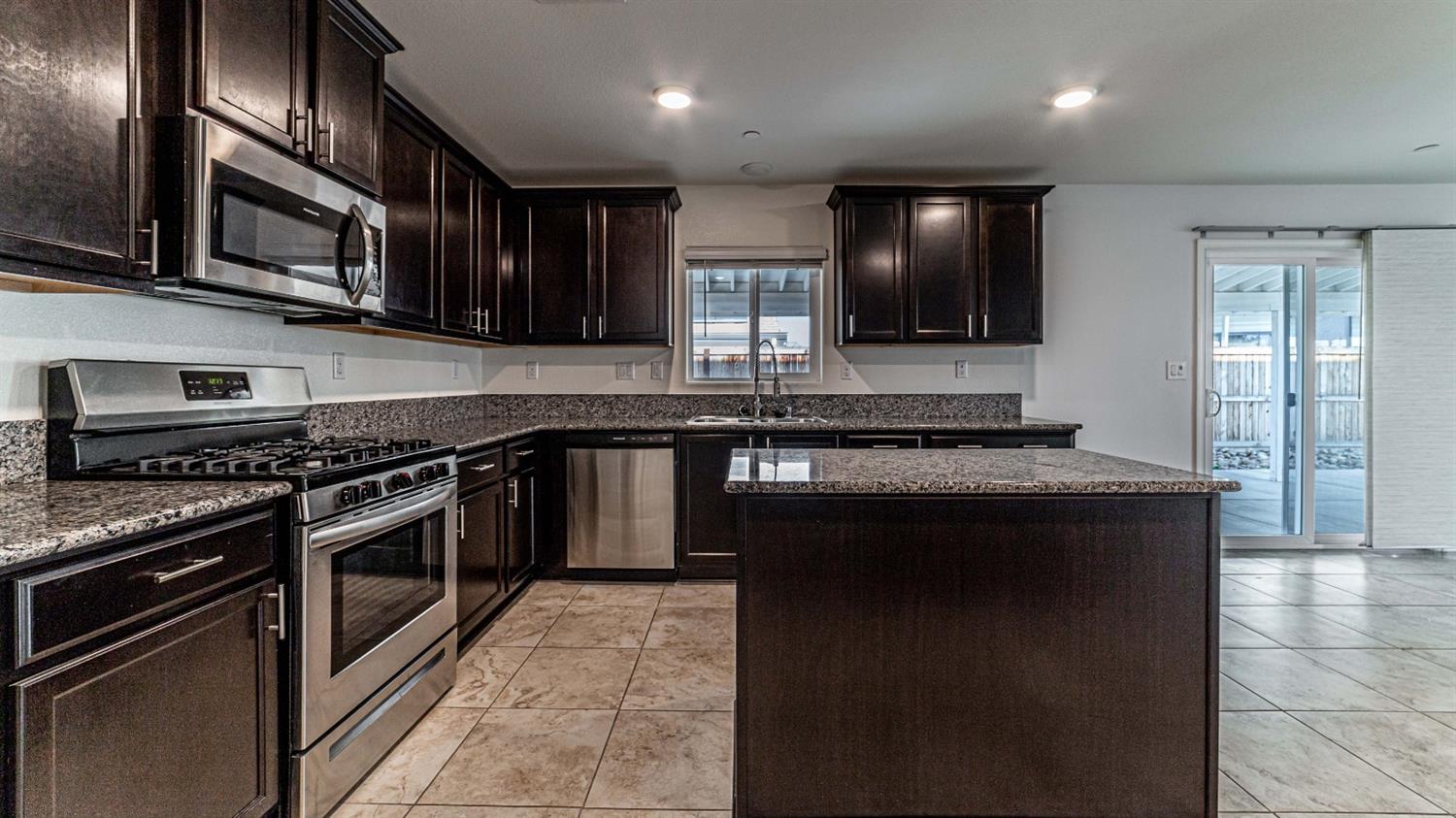 512 Barbara Avenue Sanger, CA 93657 - Photo 14 of 40 a kitchen with stainless steel appliances granite countertop a stove a sink and a microwave