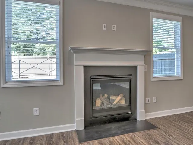 an empty room with wooden floor a ceiling fan and windows