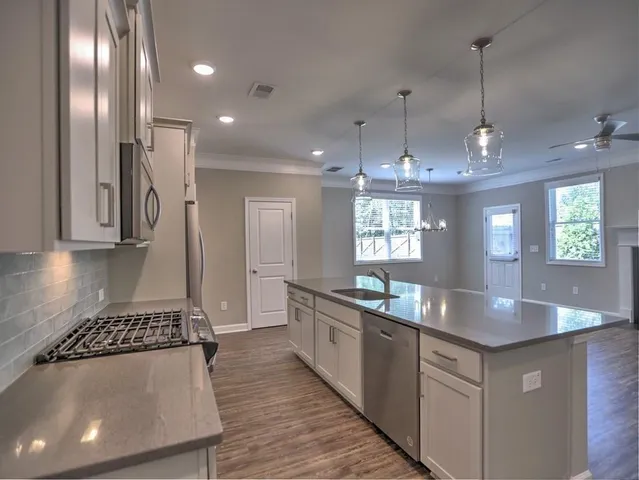 a kitchen with stainless steel appliances granite countertop a sink a stove and a wooden floors